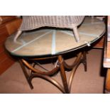 A circular glass topped garden table, on brown cane base