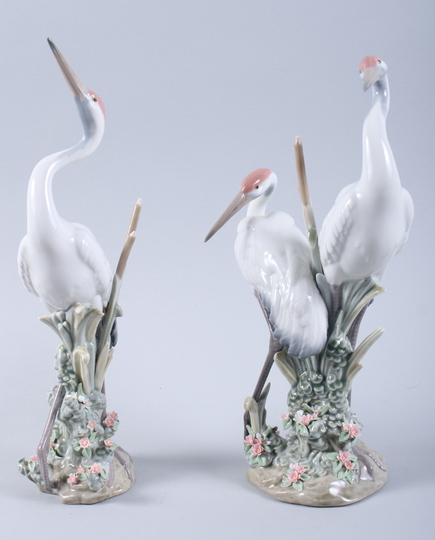 A pair of Lladro models of storks, on floral encrusted bases, 12" high