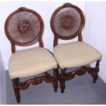 A pair of cane backed chairs, upholstered in a cream fabric, on turned 'H' stretchered supports, a