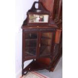 A late 19th century mahogany corner unit with raised carved mirrored back, central shelves and