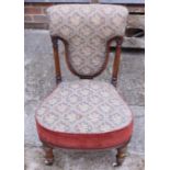 A Victorian walnut low seat nursing chair with shaped seat and back, on turned and fluted supports