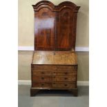 An early 18th century figured walnut double dome top bureau bookcase, the upper section with drawers