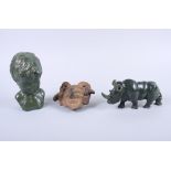 A carved green stone model of a rhinoceros, a bust of a boy, and a south American pottery head