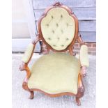 A Victorian walnut shaped showframe low armchair, upholstered in a green velvet, on carved