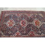A Qashqai tribal rug with three white medallions on a dark blue ground and multi-figured with