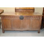 An 18th century oak and quadruple panel front coffer with planked top, on carved stile supports, 57"