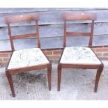 A pair of mahogany side chairs with floral embroidered drop-in seats, on sabre supports