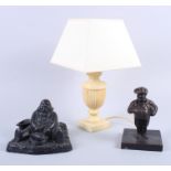 A brass inkwell, in the form of a seated man, a cast iron model of a man and a stone table lamp