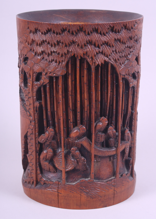 A Chinese bamboo brush pot, deeply carved with figures in a bamboo grove, 8" high