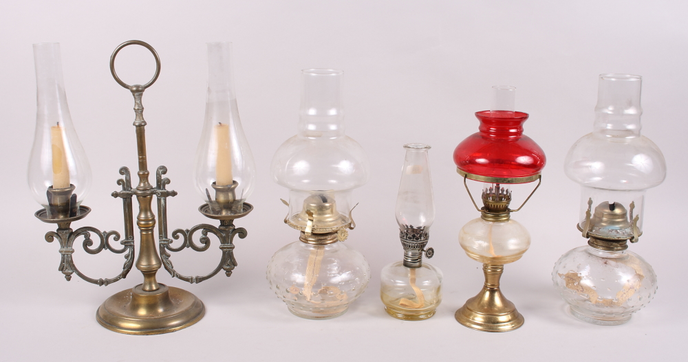 A brass two-light candelabra with glass shades and four oil lamps