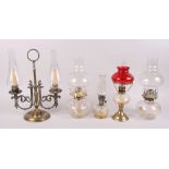 A brass two-light candelabra with glass shades and four oil lamps
