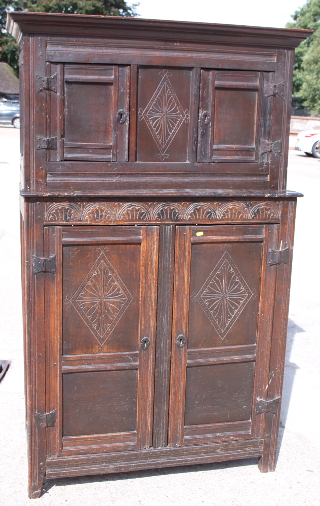 A late 17th century carved oak duedarn, the upper section enclosed two doors over two further doors,