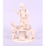 A Japanese sectional ivory okimono of a toy seller with children, 6 1/4" high