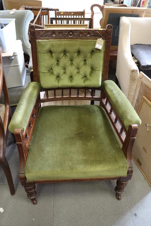 A late Victorian carved oak open armchair, button upholstered in a green Dralon, on turned and