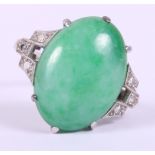 An Art Deco white metal ring, set jade cabochon, flanked three diamonds to each shoulder, ring
