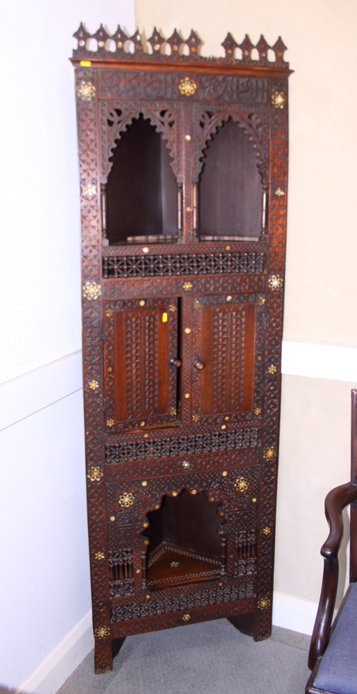 An antique Moorish floor standing corner cabinet, with script carved frieze, carved, turned and