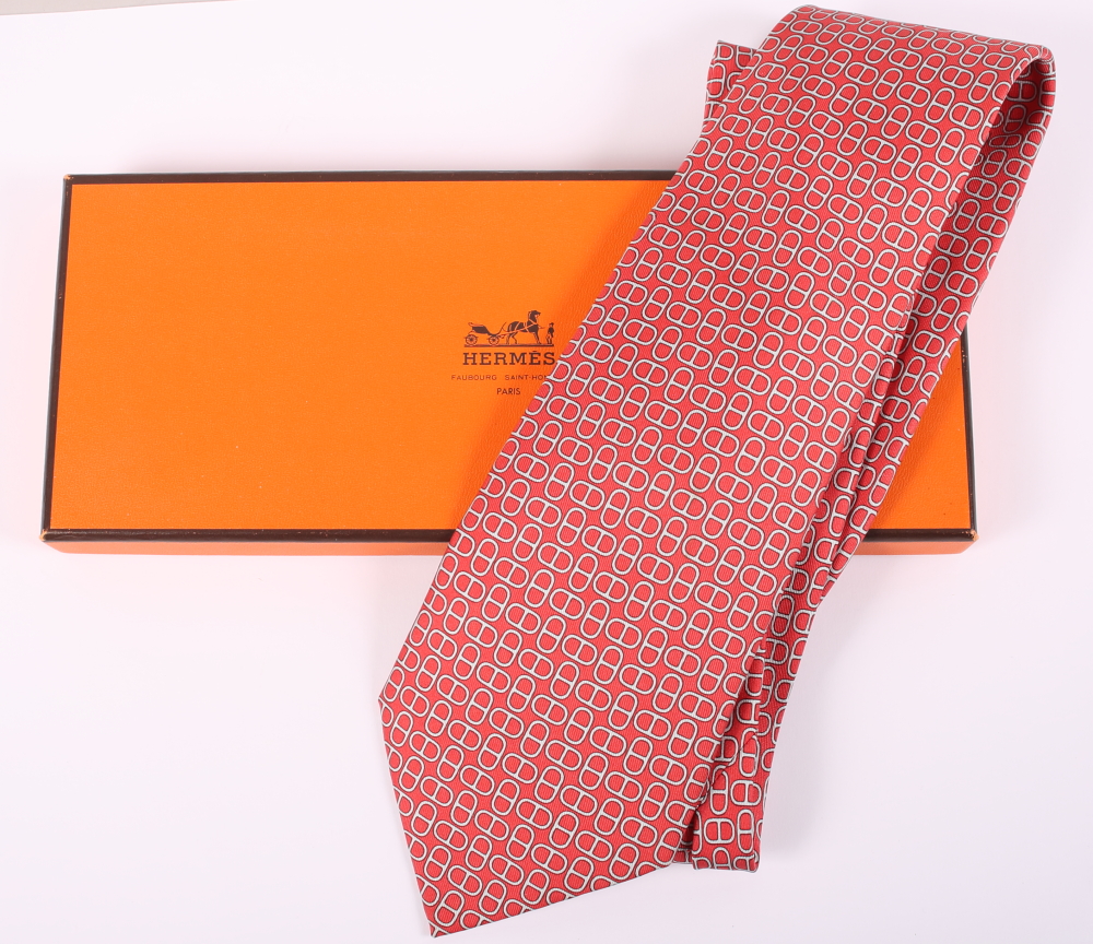 A Hermes silk tie with all-over red and grey geometric pattern, complete with box