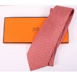 A Hermes silk tie with all-over red and grey geometric pattern, complete with box