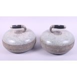A pair of curling stones with black and white metal handles