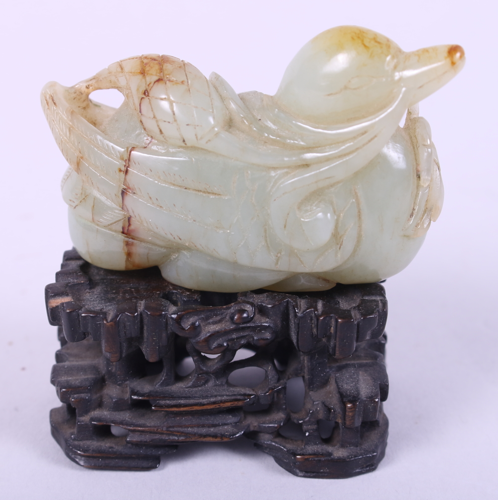 A Chinese carved pale celadon jade figure of a duck, 2 3/4" long, on associated carved hardwood
