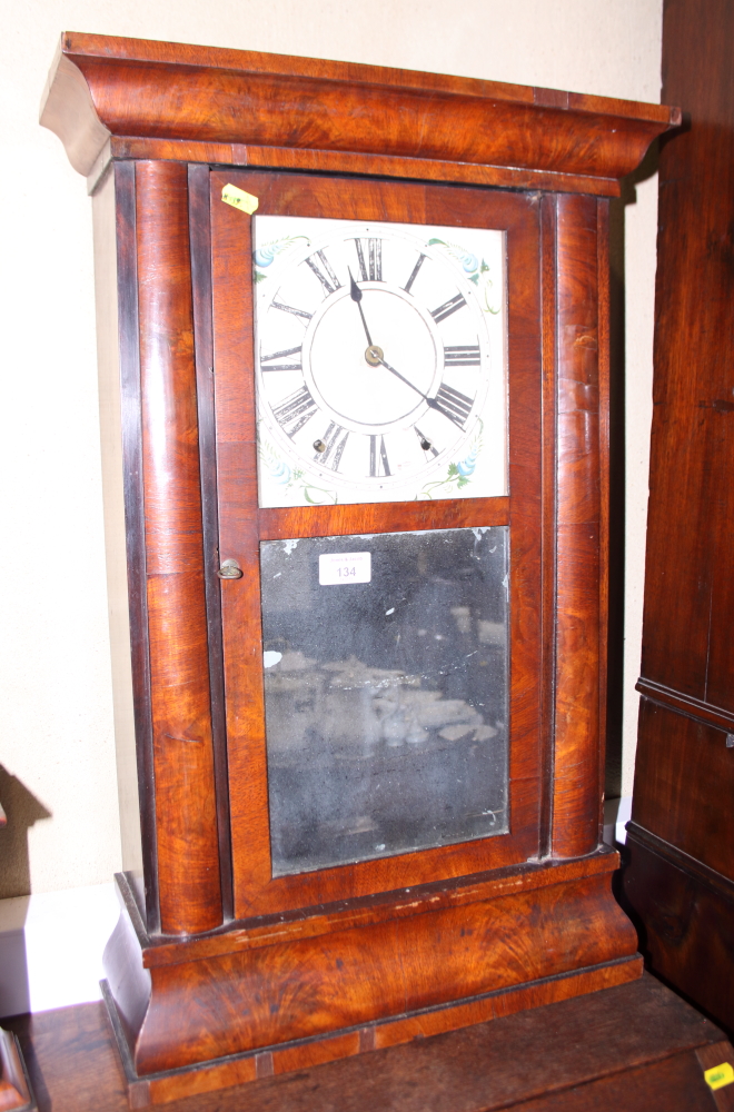 A mahogany cased Vienna wall clock with white painted dial and Arabic numerals above a mirrored