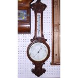 A late 19th century oak cased aneroid barometer and thermometer