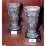 A pair of anodised metal beakers with bacchanalian scenes, on marble bases, 7" high