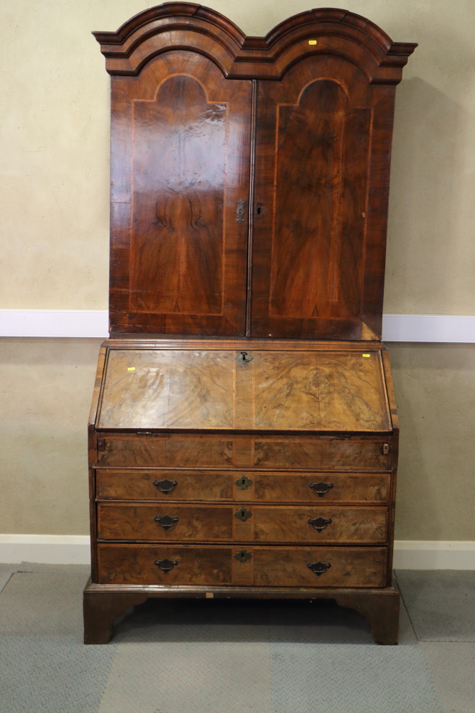 An early 18th century figured walnut double dome top bureau bookcase, the upper section with drawers