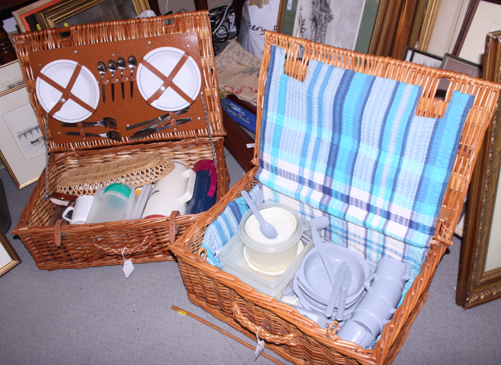 Two wicker picnic baskets with cutlery, plates and flasks