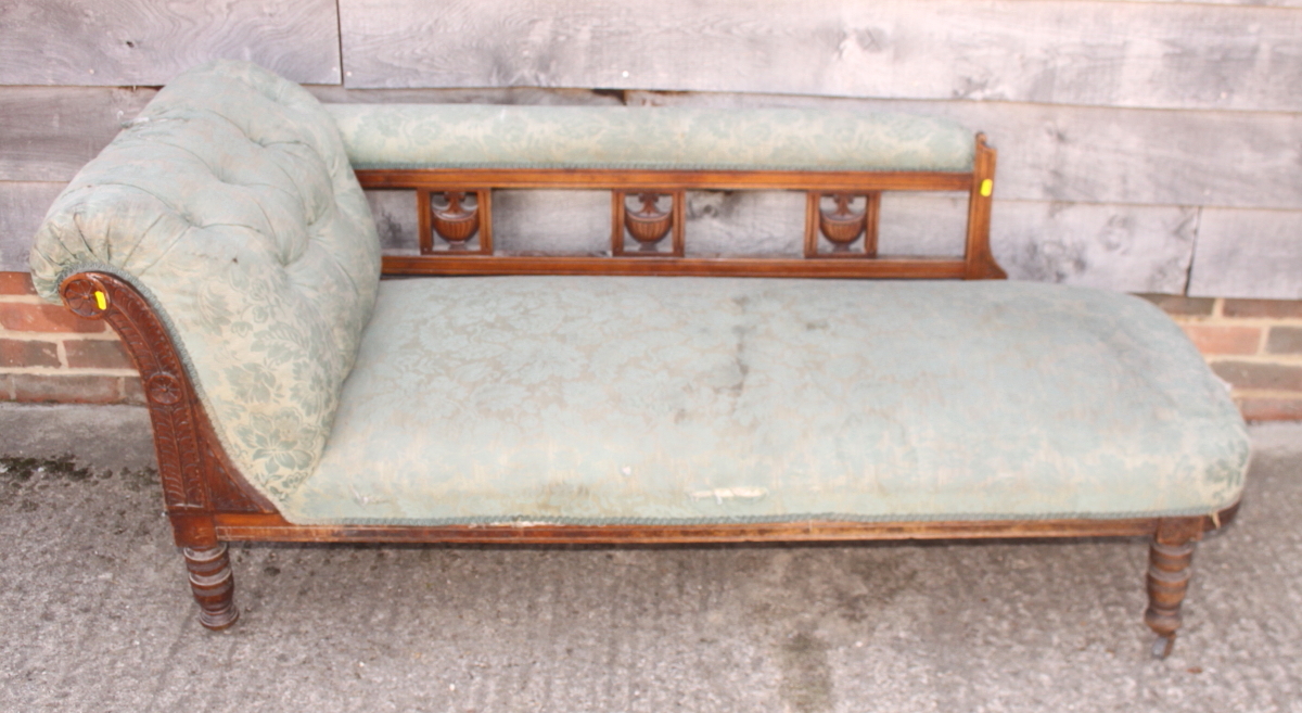 A late 19th century chaise longue with carved scroll end and vase splats to back, upholstered in