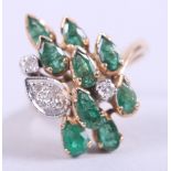 A yellow metal dress ring, stamped 585, set with emeralds and diamonds, size K, 6.8g