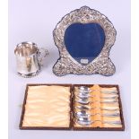 An embossed silver photograph frame, decorated cherubs, a cased set of six silver plated coffee