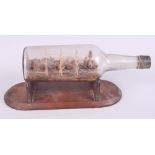 A 19th century ship in a bottle, on wooden stand