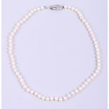 A single strand pearl necklace, 19" long, with white metal and diamond set clasp