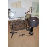 A black japanned table lamp, a studio lamp, one other lamp and a wrought iron spark guard