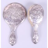 An embossed silver dressing table mirror, decorated Reynolds Angels, and a similar hairbrush