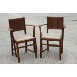 A pair of Ercol oak panel back elbow chairs with drop-in faux leather seats, on moulded and