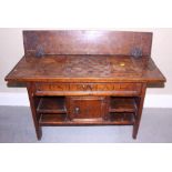An Iberian carved walnut games table with drawer and cupboard, on panel end supports, inscribed "Dos