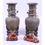 A pair of Chinese bronze vases with relief cast dragon decoration to the necks, on wooden stands, 11
