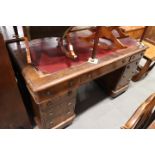 An oak double pedestal desk with brown leather tooled lined top, fitted nine drawers, on block base,