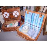 Two wicker picnic baskets with cutlery, plates and flasks