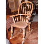 A child's Windsor stick back rocking elbow chair with elm panel seat