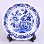 A 19th century English delft dish, decorated with flowers and fence, 9" dia