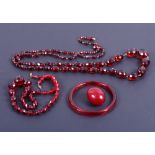A graduated "cherry amber" coloured faceted bead necklace, 40" long, a similar smaller necklace, and