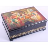 A Russian lacquer box, decorated with royal feast and scrolled borders
