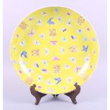 A Chinese porcelain charger, decorated butterflies and characters on a yellow ground, 13 1/2" dia