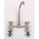A Victorian style brass kitchen tap with two handles and central curved spout