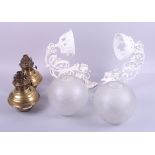 A pair of brass oil lamps with white painted floral and scrolled wall brackets and spherical