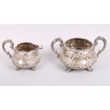 A silver sugar bowl, a matching cream jug with embossed heavy scrolled and floral decoration, 21.1oz