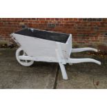 An early 20th century white painted wooden garden wheelbarrow, 62" long
